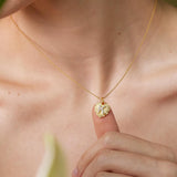 Gold necklace with a heart-shaped pendant being held by a person
