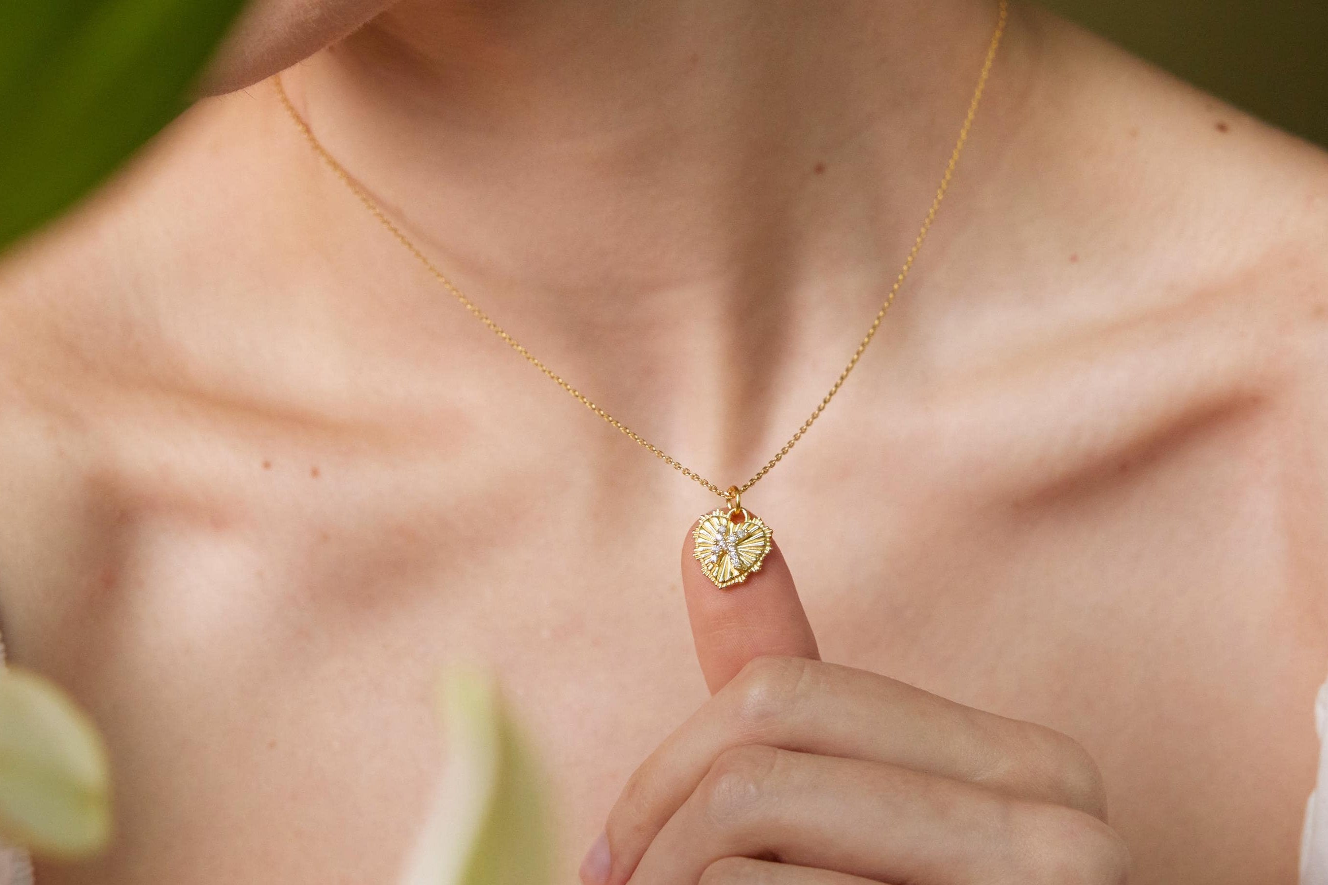 Gold necklace with a heart-shaped pendant being held by a person