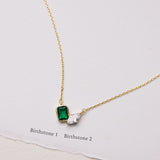 Gold necklace with a green gemstone pendant on a white background