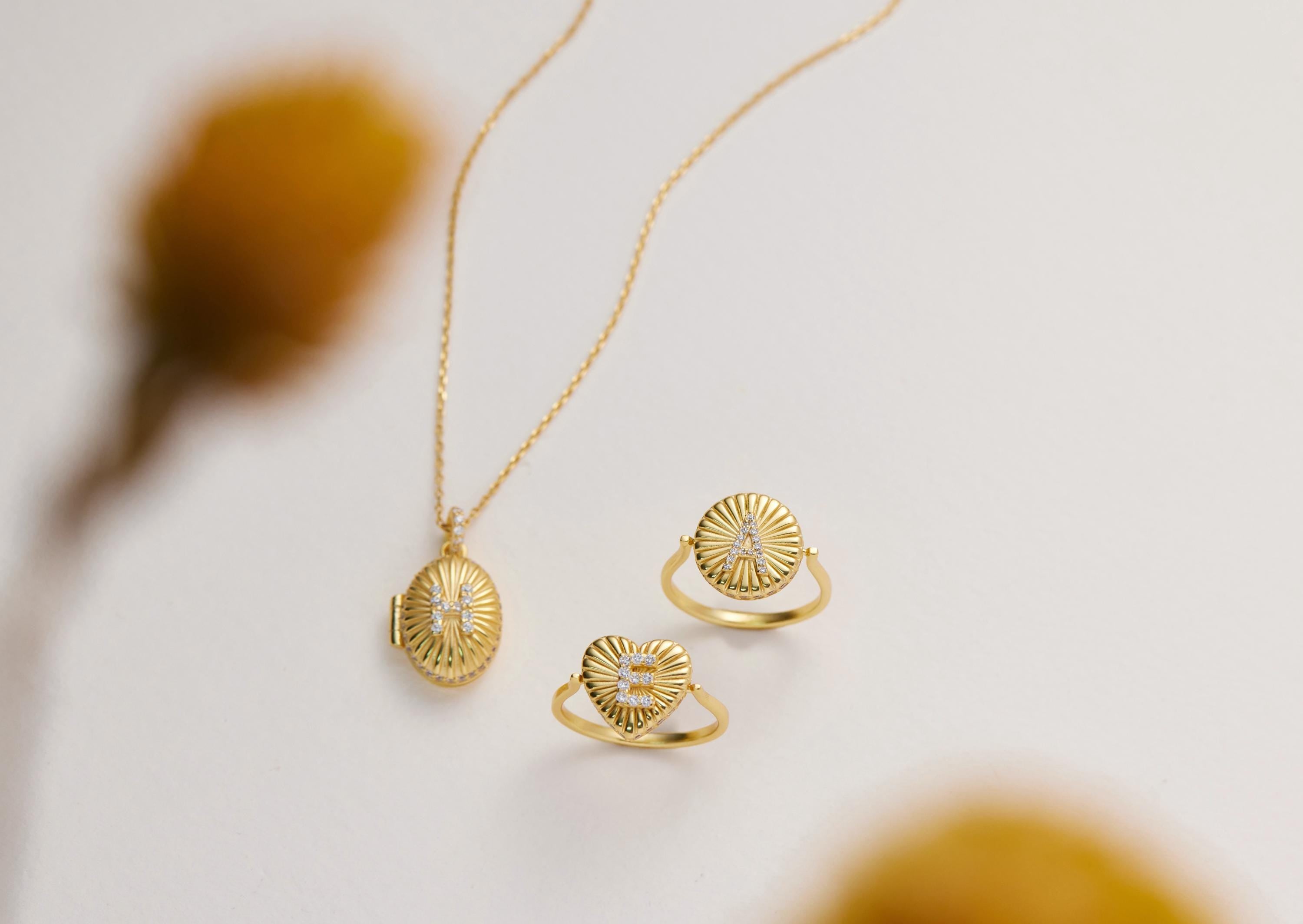 a necklace, two rings, and a locket, all made of gold and adorned with intricate designs.