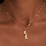 Gold necklace with a pendant featuring paw prints on a brown background