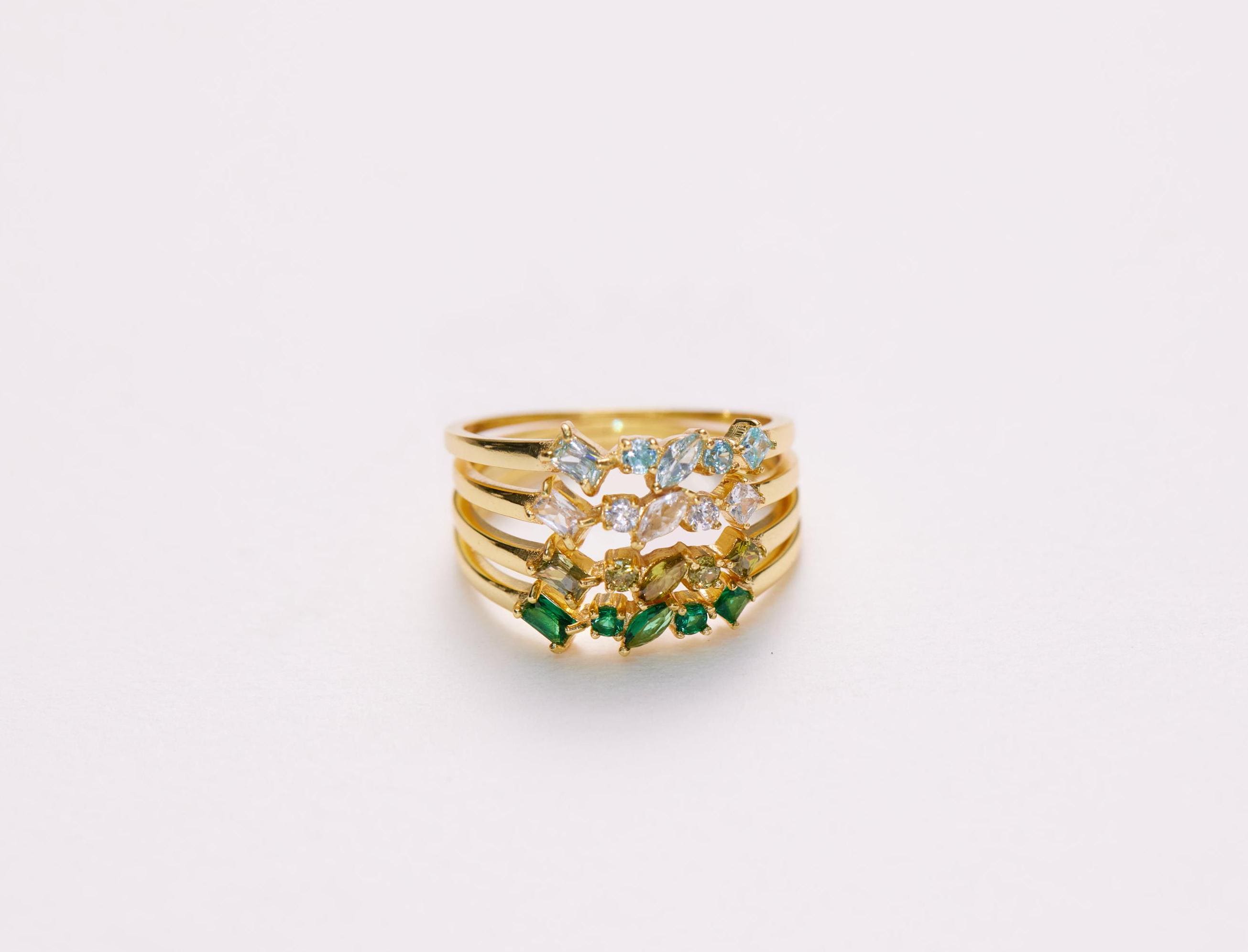 Gold ring with gemstones on a light gray background