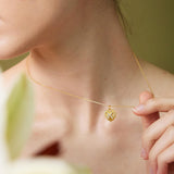 Close-up of a person wearing a gold necklace with a heart-shaped pendant.