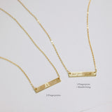 Two gold bar necklaces on a light gray background