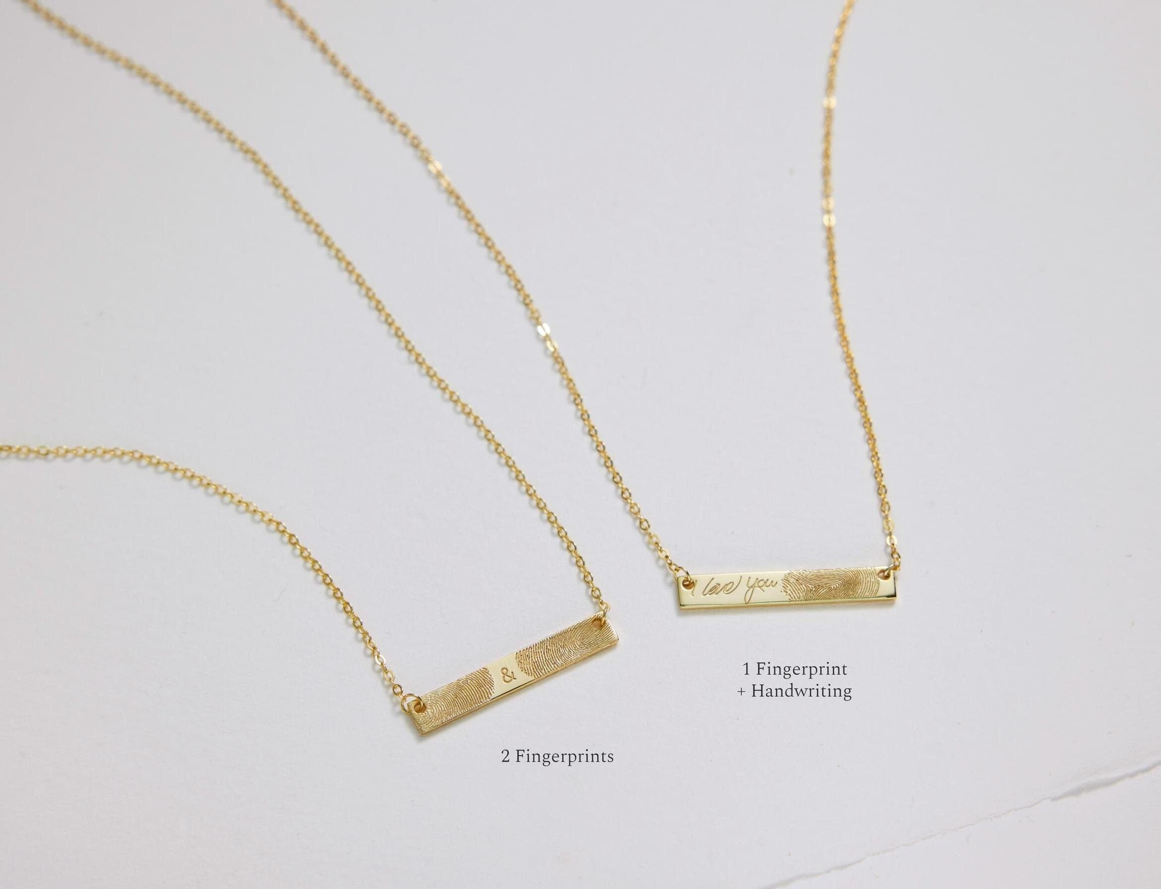 Two gold bar necklaces on a light gray background