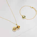 Gold necklace and bracelet with embedded stones on a light gray background