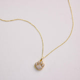 Gold necklace with a diamond pendant on a light gray background