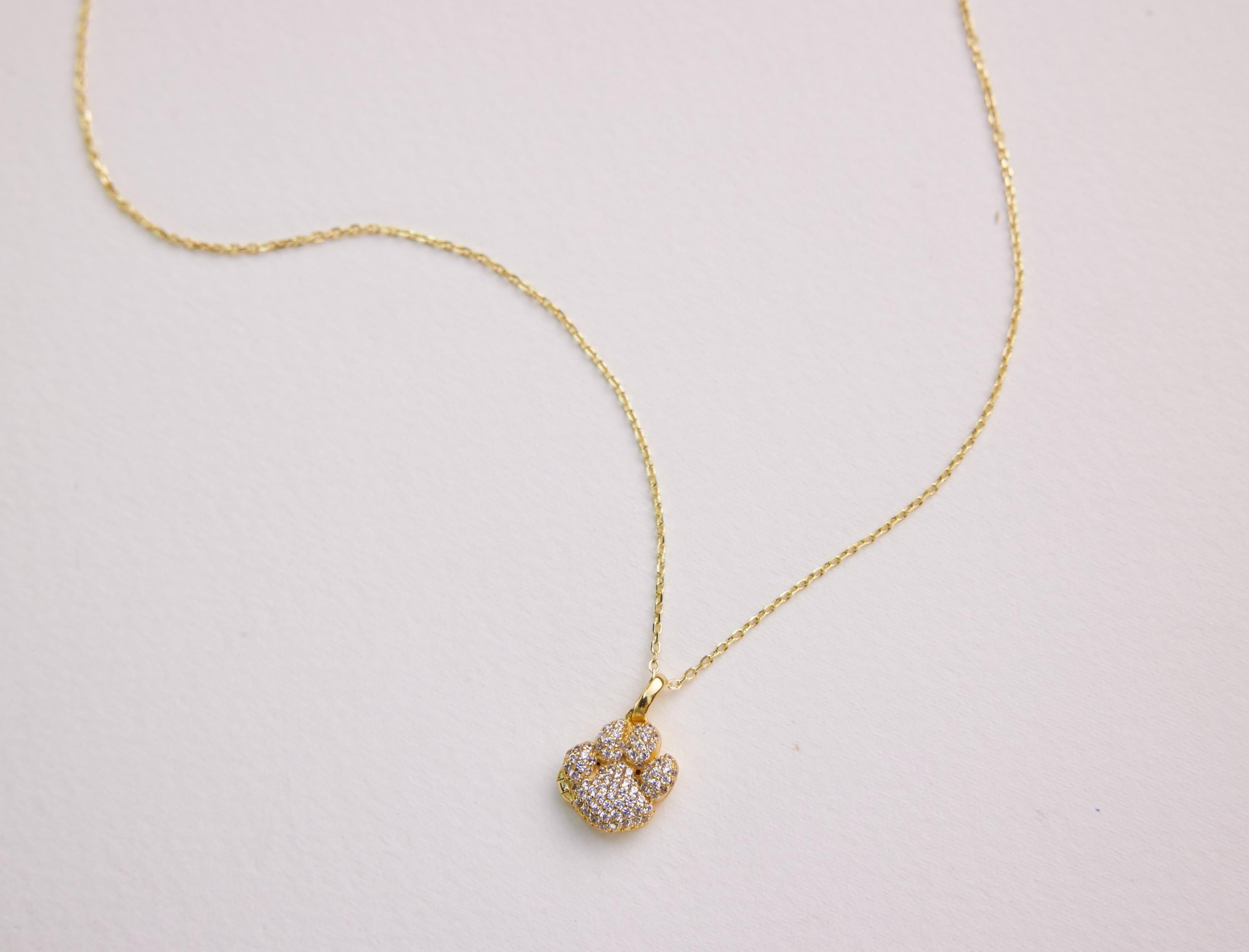 Gold necklace with a diamond pendant on a light gray background