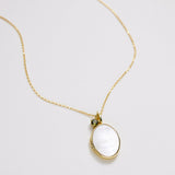 Gold necklace with a pendant on a light gray background
