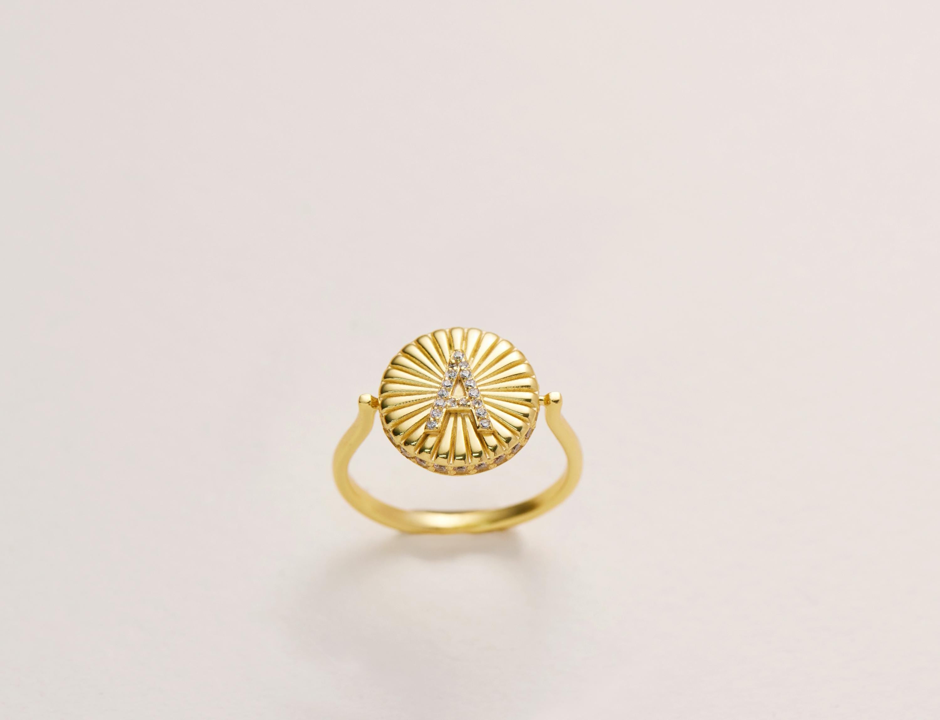 A gold ring with a letter &quot;A&quot; on it, which appears to be a personalized piece of jewelry.