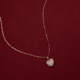 Gold necklace with a heart-shaped pendant on a red background