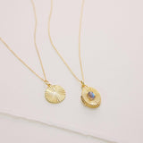 Two gold necklaces with circular pendants on a light background