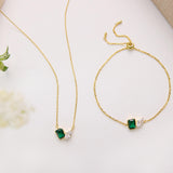 a collection of gold jewelry, including necklaces and bracelets, with green and white gemstones.