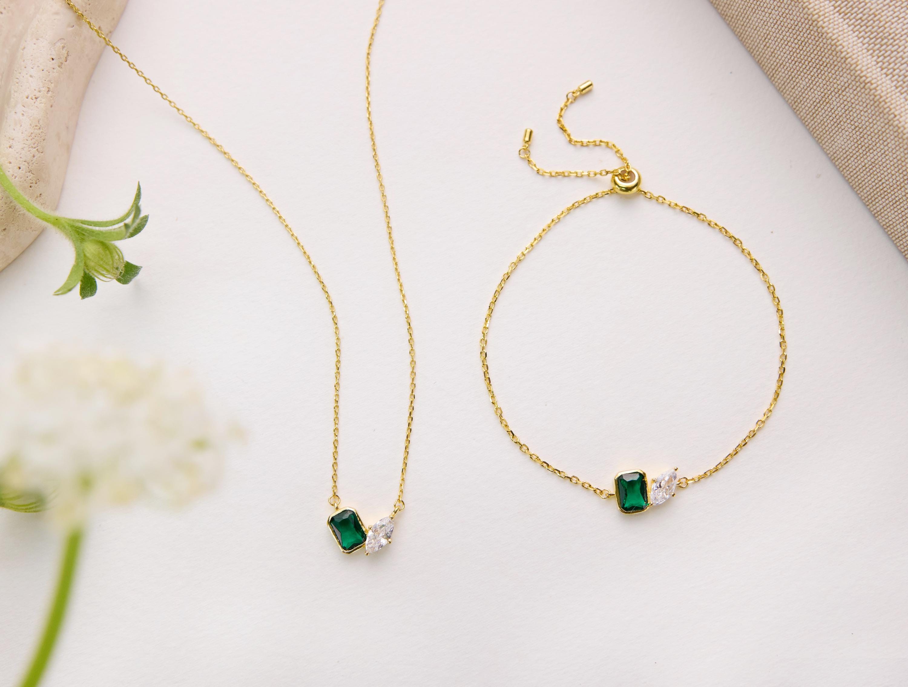 a collection of gold jewelry, including necklaces and bracelets, with green and white gemstones.