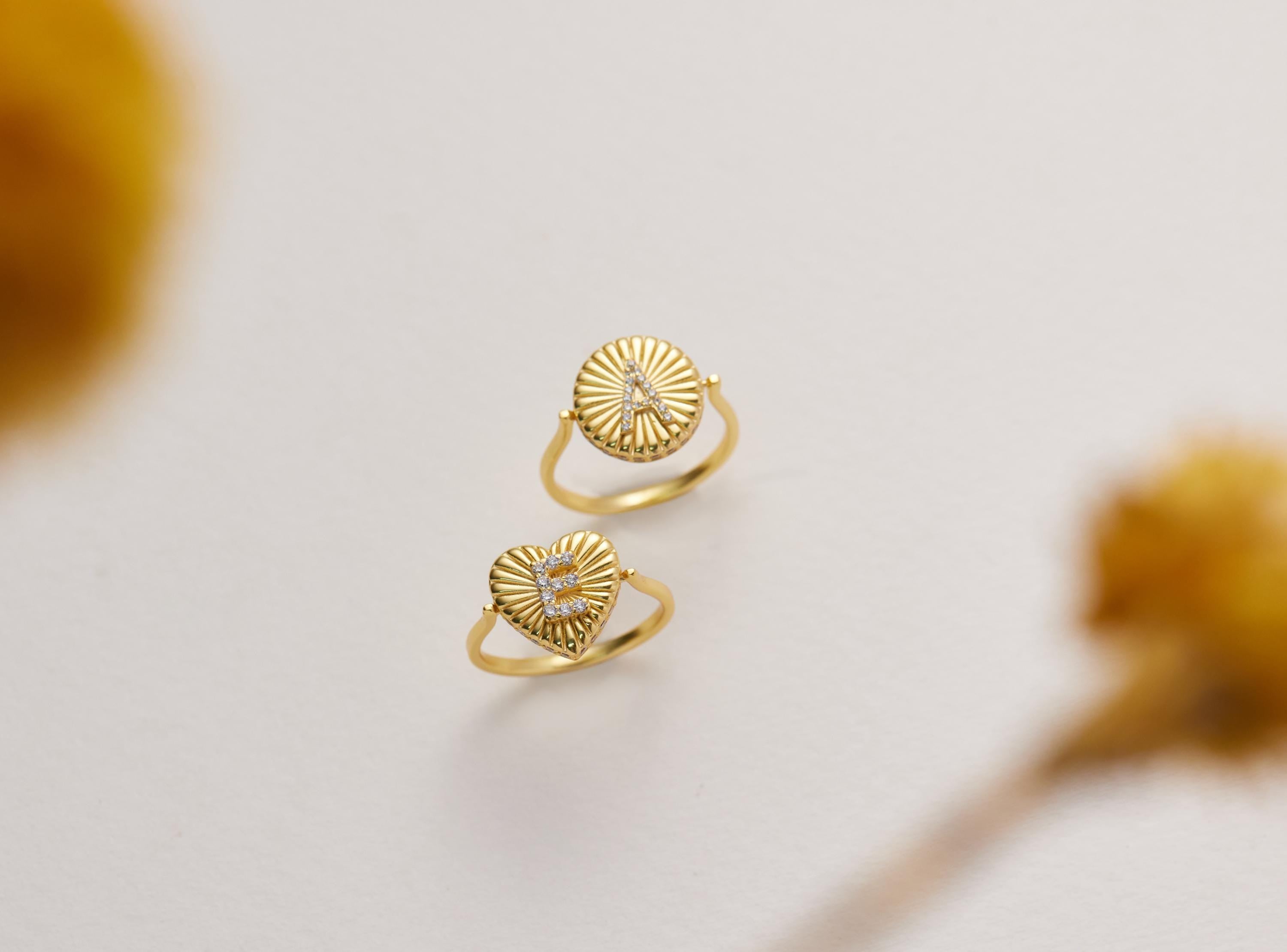 Two gold rings with unique designs are displayed against a white background.