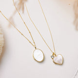 Two gold necklaces with heart-shaped pendants on a light background