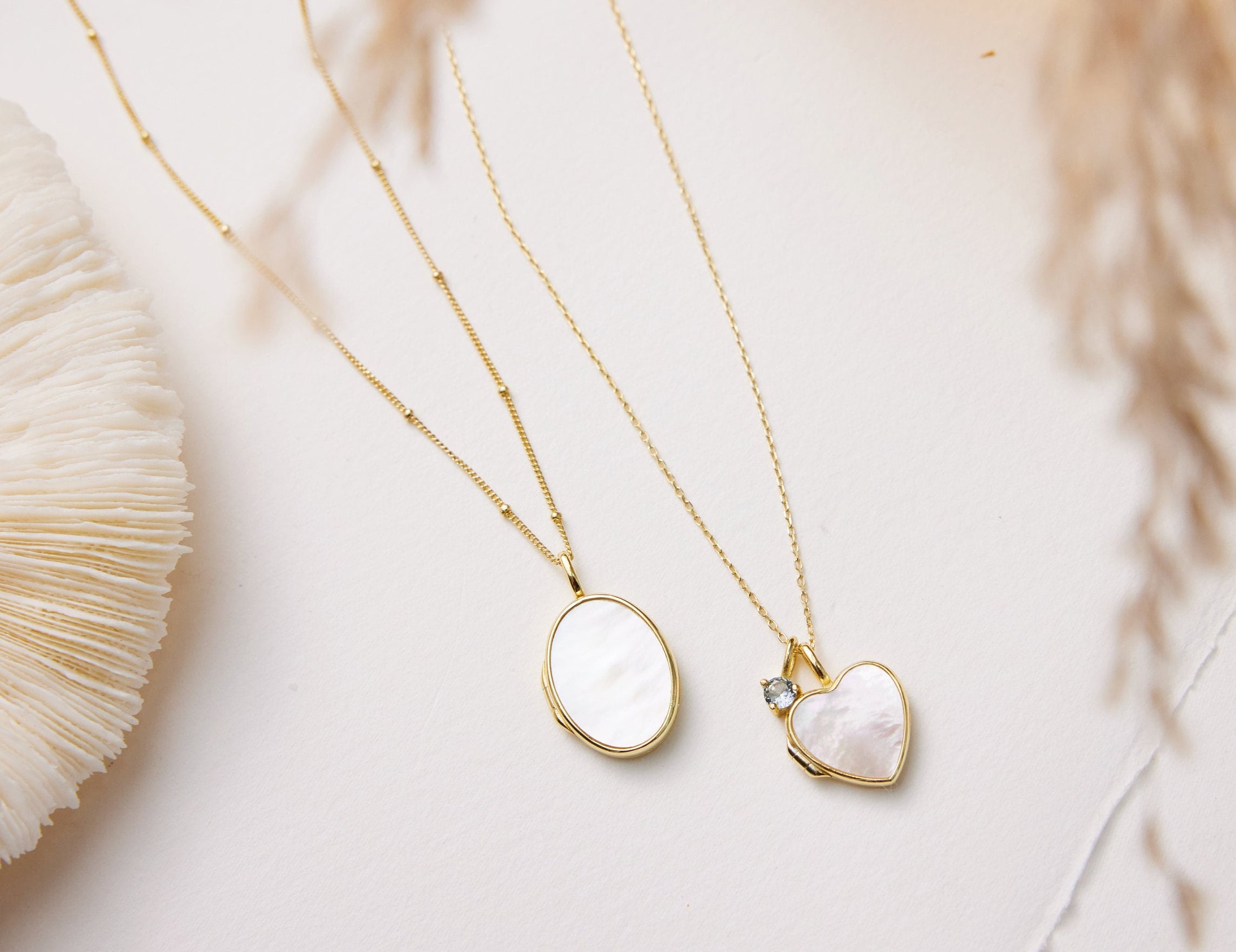 Two gold necklaces with heart-shaped pendants on a light background