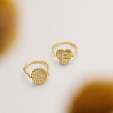 Two gold rings with heart-shaped designs are displayed on a white background.