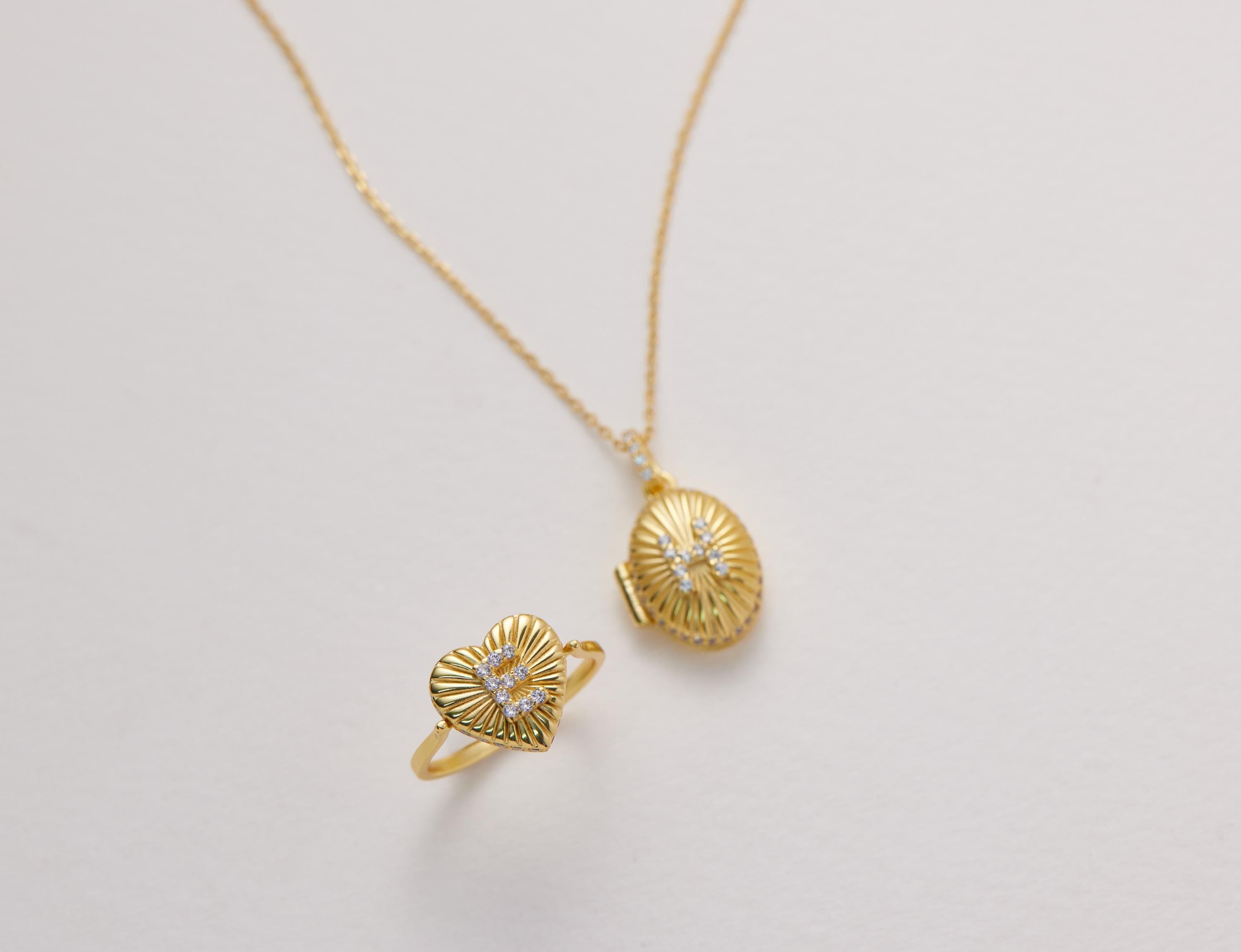 a gold necklace and a gold ring with a heart-shaped design, both adorned with small diamonds.