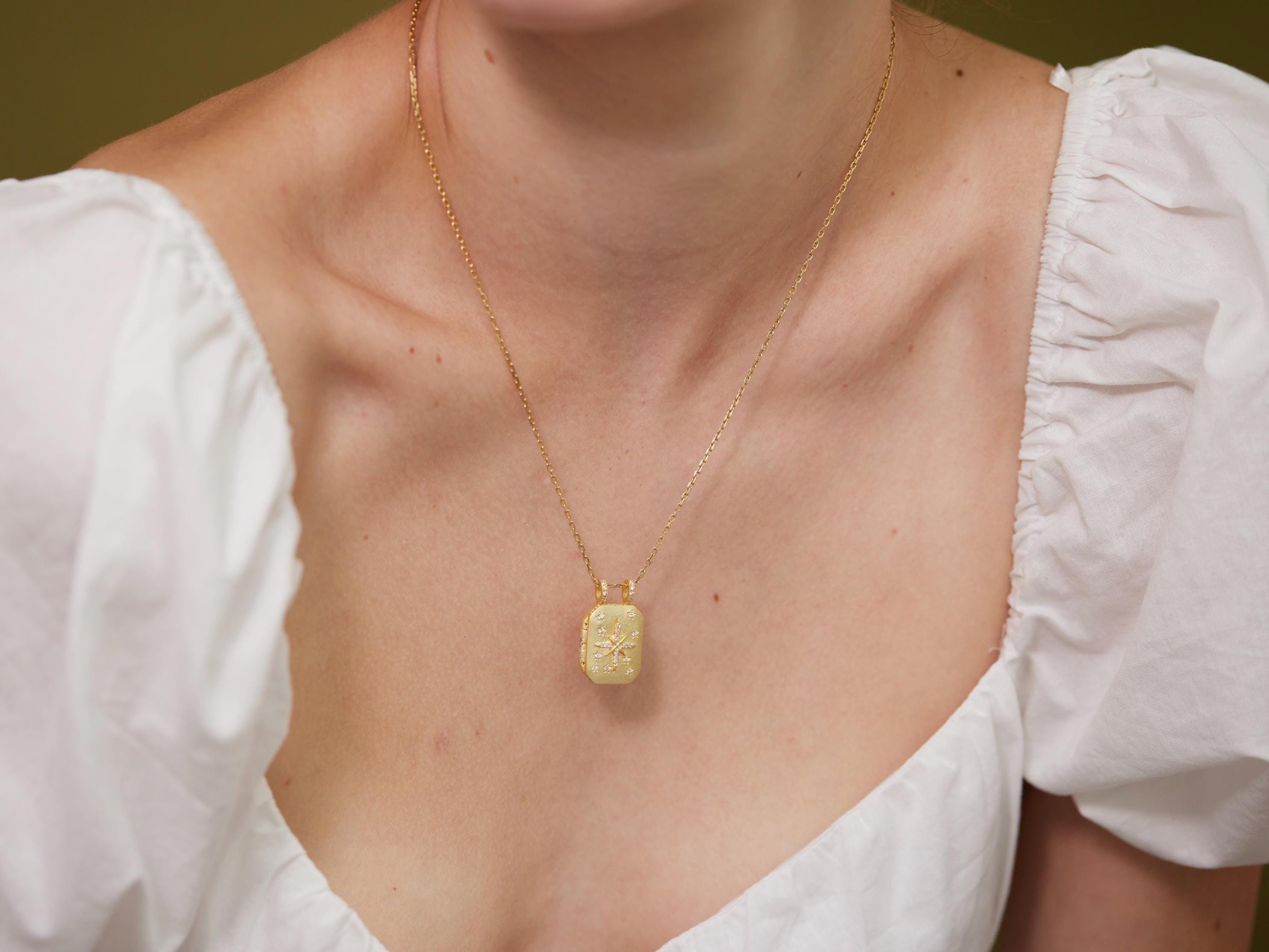 A close-up of a woman wearing a gold necklace with a pendant.