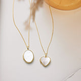 Two gold necklaces with heart-shaped pendants on a neutral background