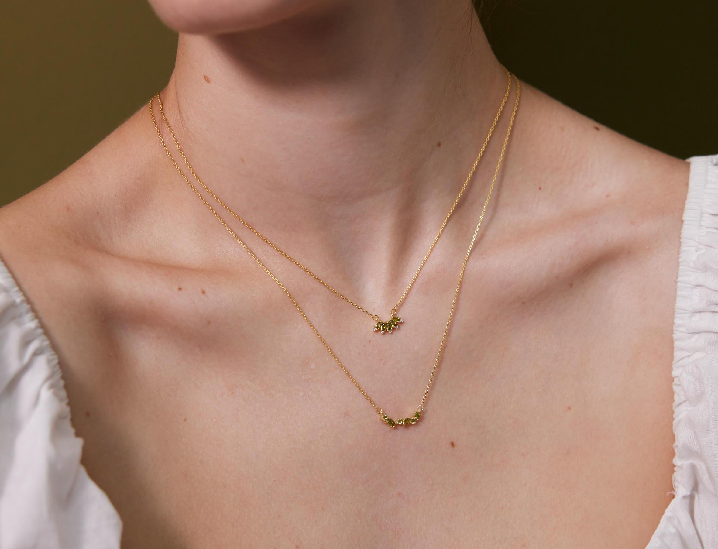 Close-up of a person wearing a delicate gold necklace with a small pendant on a neutral background