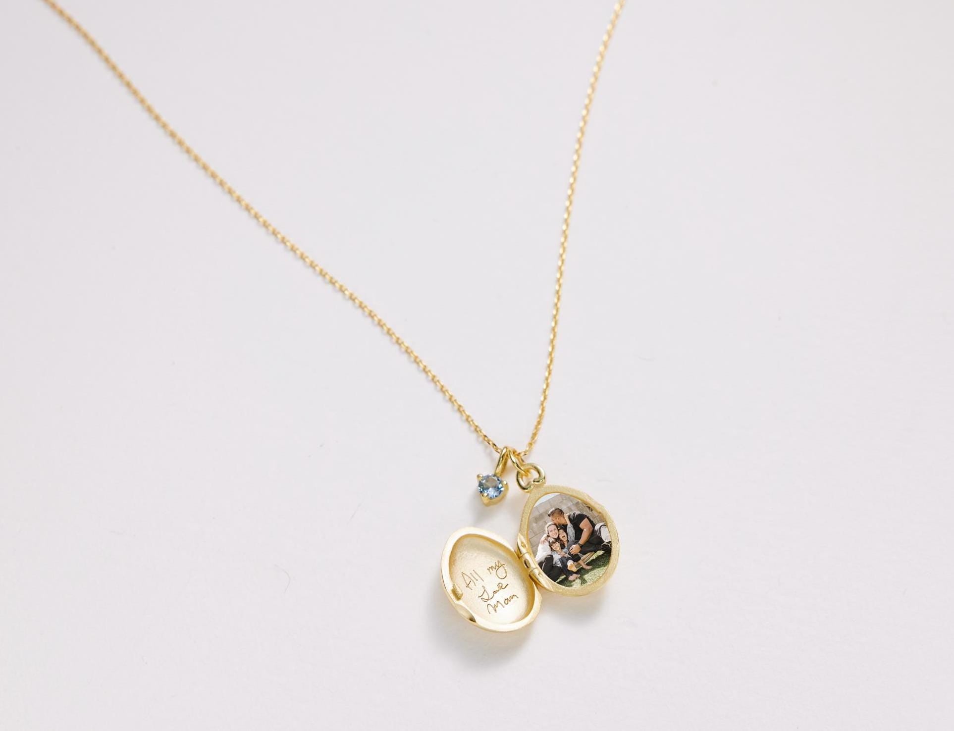 Gold necklace with a locket pendant on a light gray background