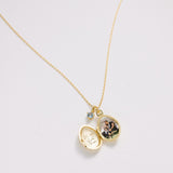 Gold necklace with a locket pendant on a light gray background