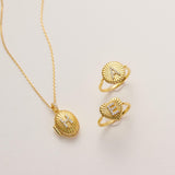 A gold necklace with a pendant and two gold rings with heart-shaped designs are displayed on a white background.
