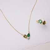 Gold necklace and ring with green gemstones on a light background