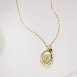 Gold necklace with a pendant featuring an engraved letter 'L' on a light background