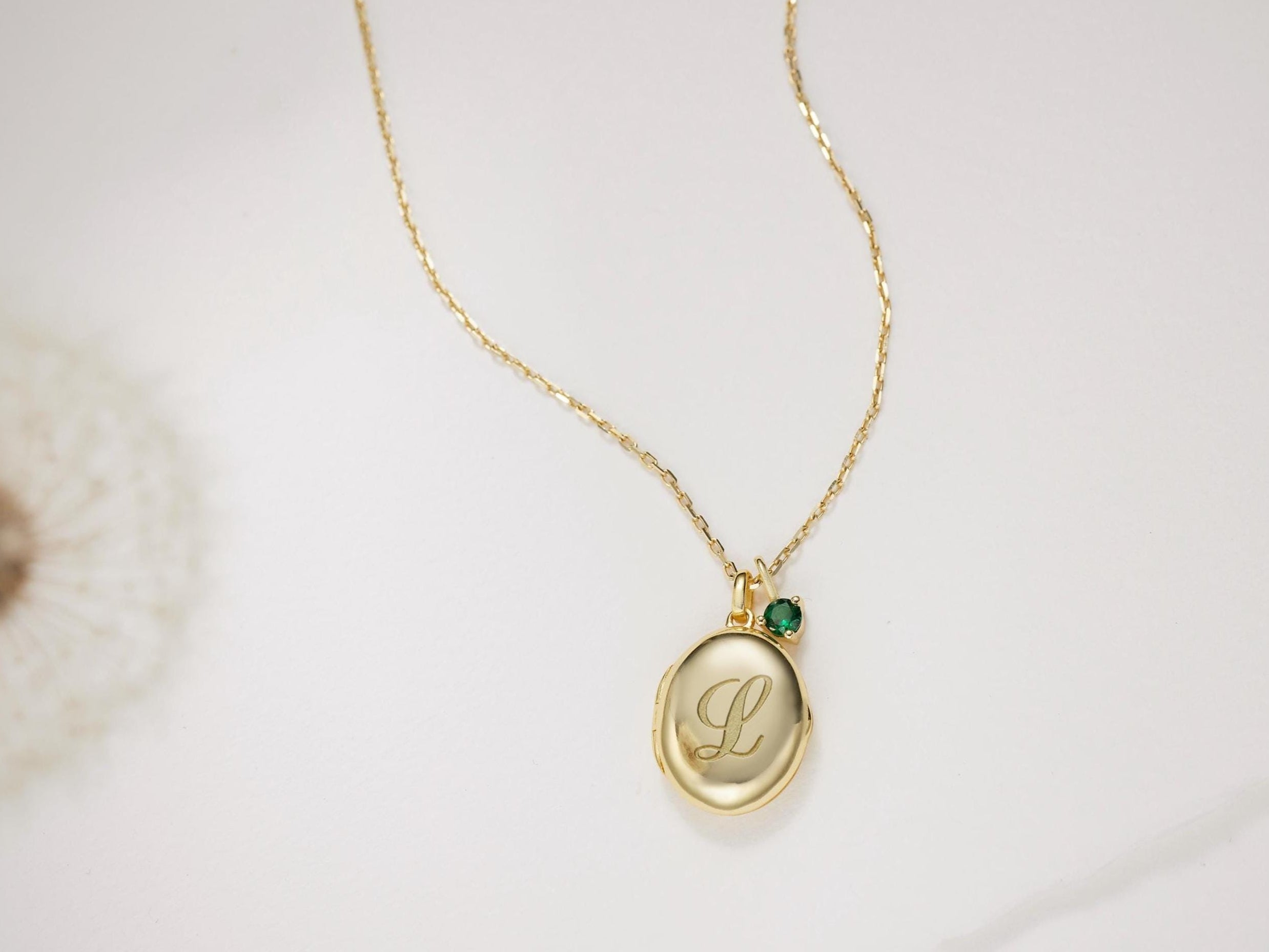 Gold necklace with a pendant featuring an engraved letter 'L' on a light background