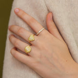 A close-up of a person's hand wearing three gold rings on the fingers.