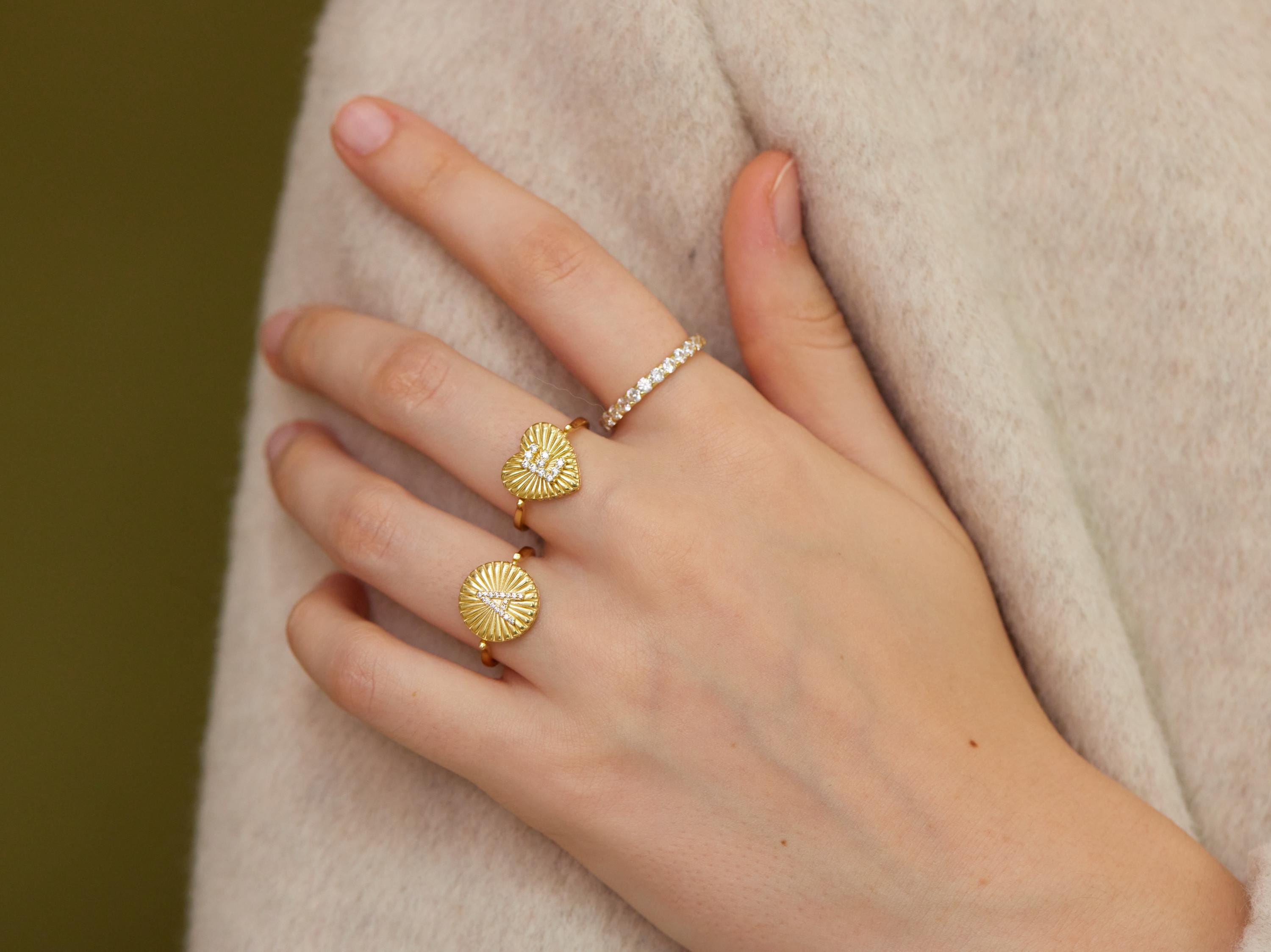 A close-up of a person's hand wearing three gold rings on the fingers.