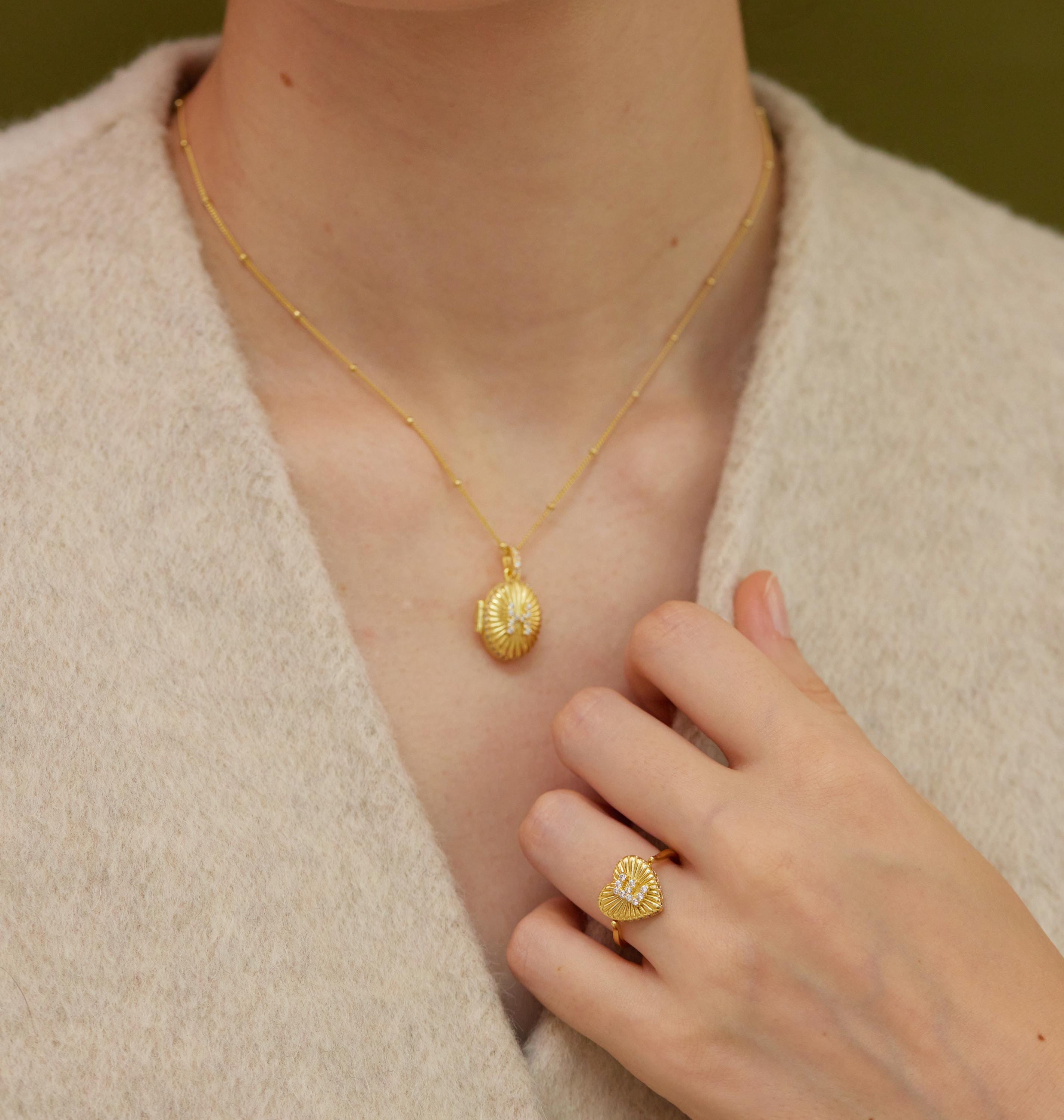 A close-up view of a person's neck and hand wearing a gold necklace and ring.