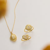 a necklace, two rings, and a locket pendant, all made of gold and displayed on a white background.