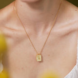 A close-up of a woman wearing a gold necklace with a small pendant.