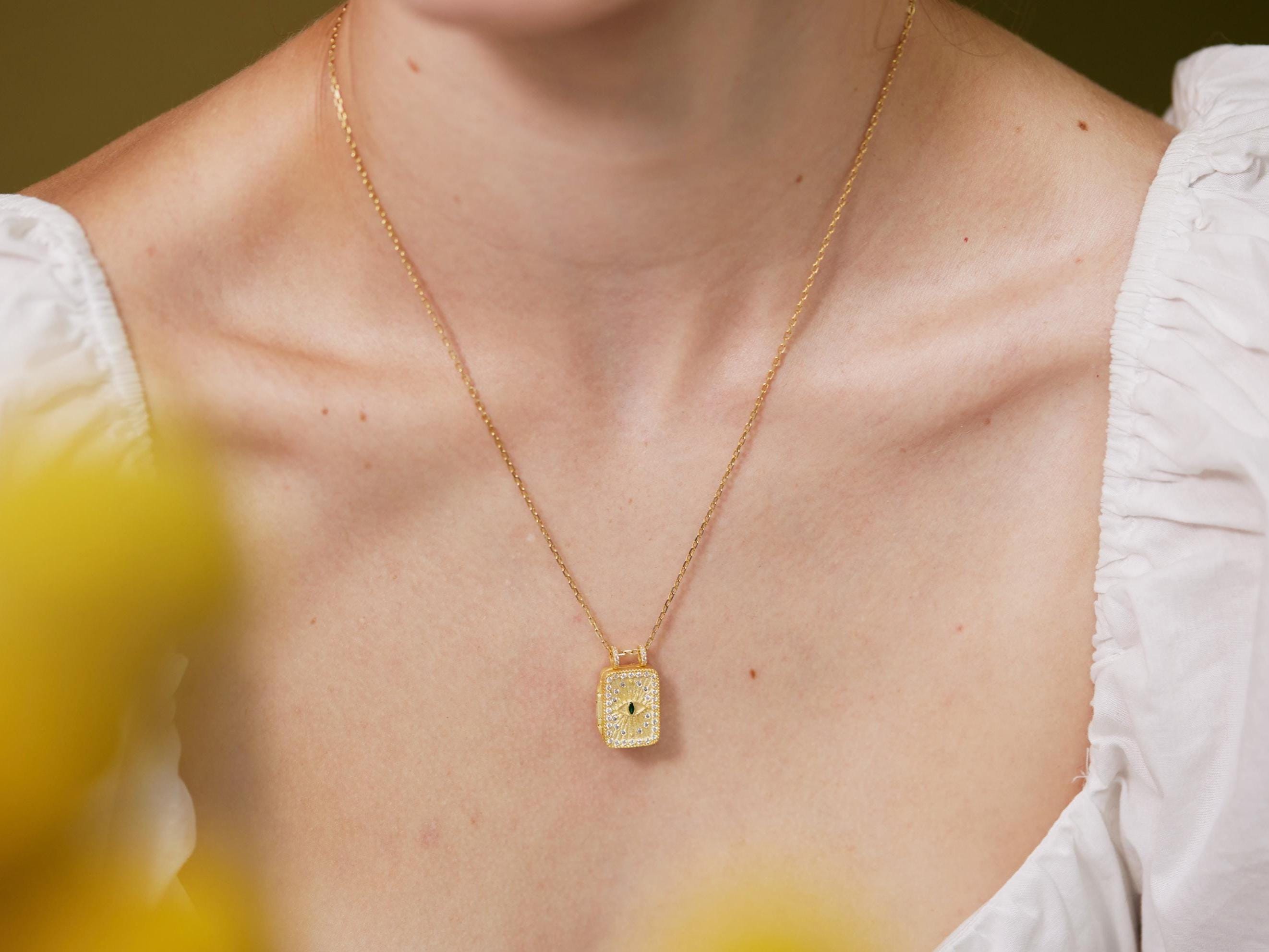 A close-up of a woman wearing a gold necklace with a small pendant.
