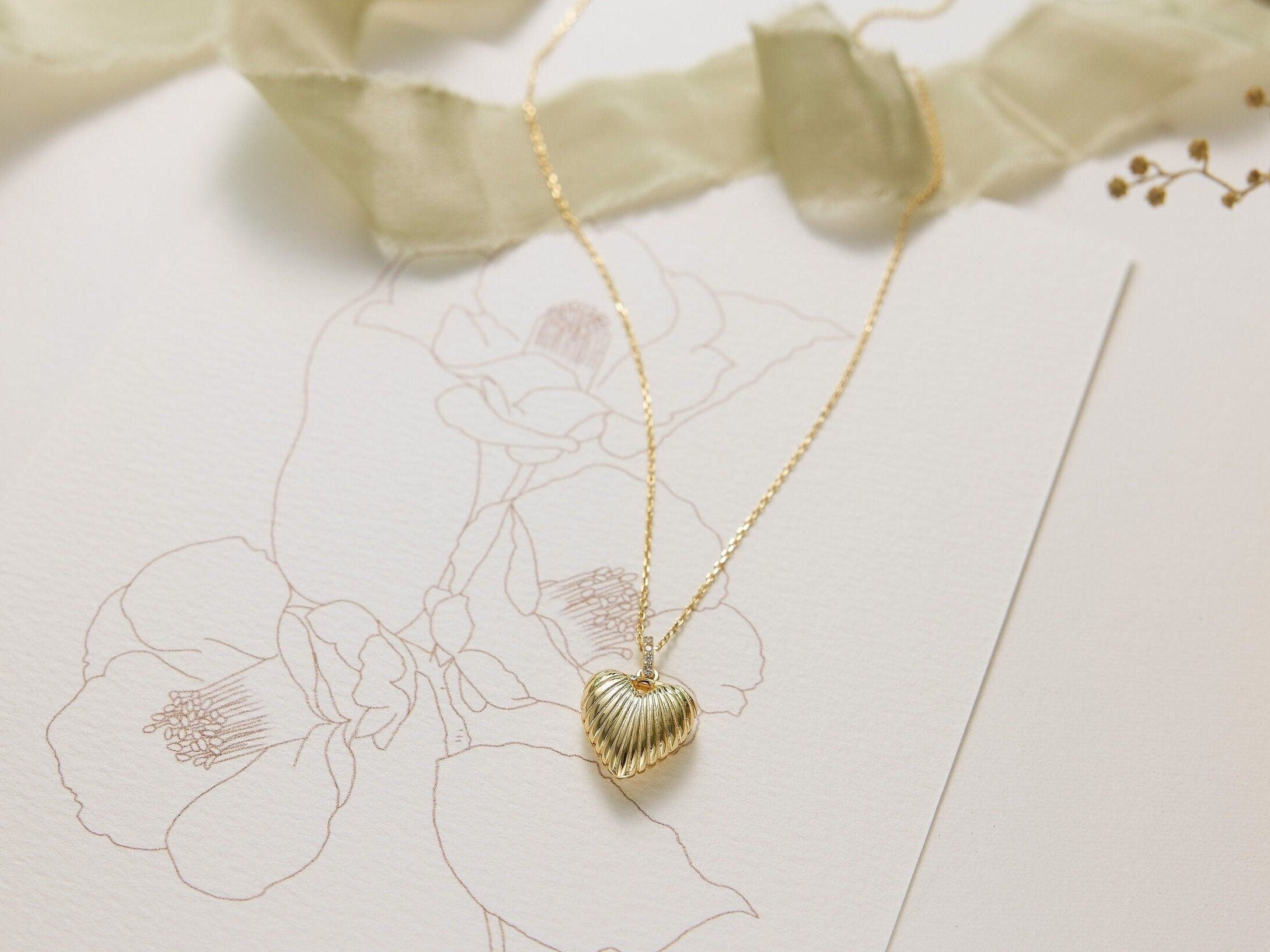Gold necklace with a heart pendant on a floral card