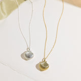Two shell-shaped pendant necklaces on a light background