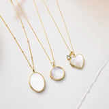 Three gold necklaces with different pendants on a light background