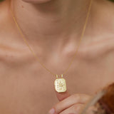 A close-up of a person's neck and chest area wearing a gold necklace with a pendant.