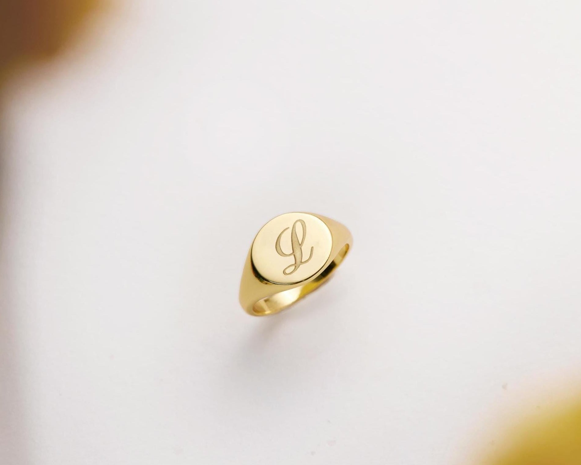 Gold ring with a monogram on a light background