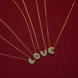 Gold necklaces with 'LOVE' pendants on a red background