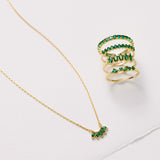 Gold necklace and ring with green gemstones on a white background