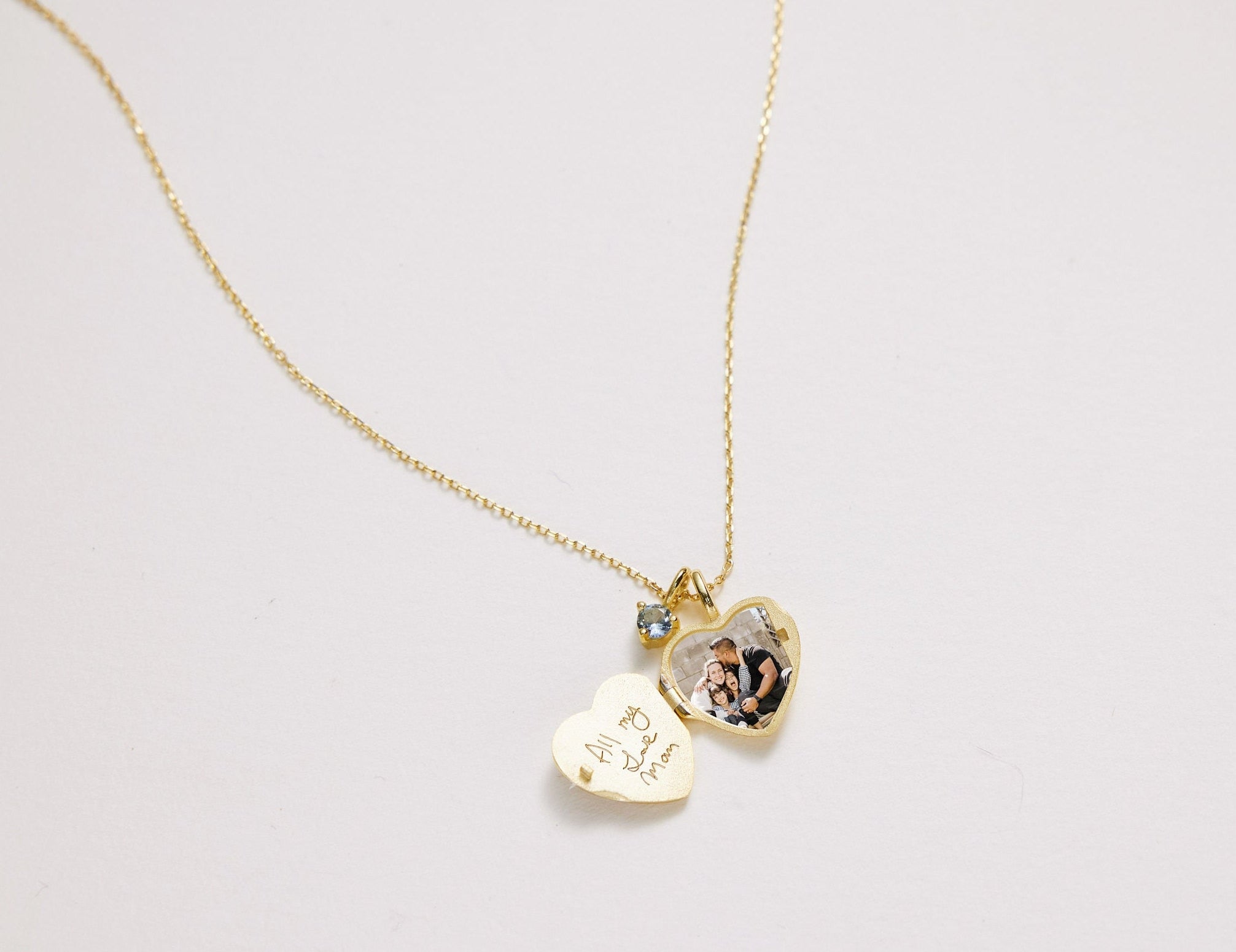 Gold necklace with heart-shaped pendants on a light gray background