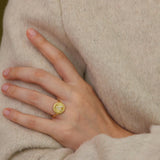 A close-up of a person&#39;s hand wearing a gold ring with a circular design.