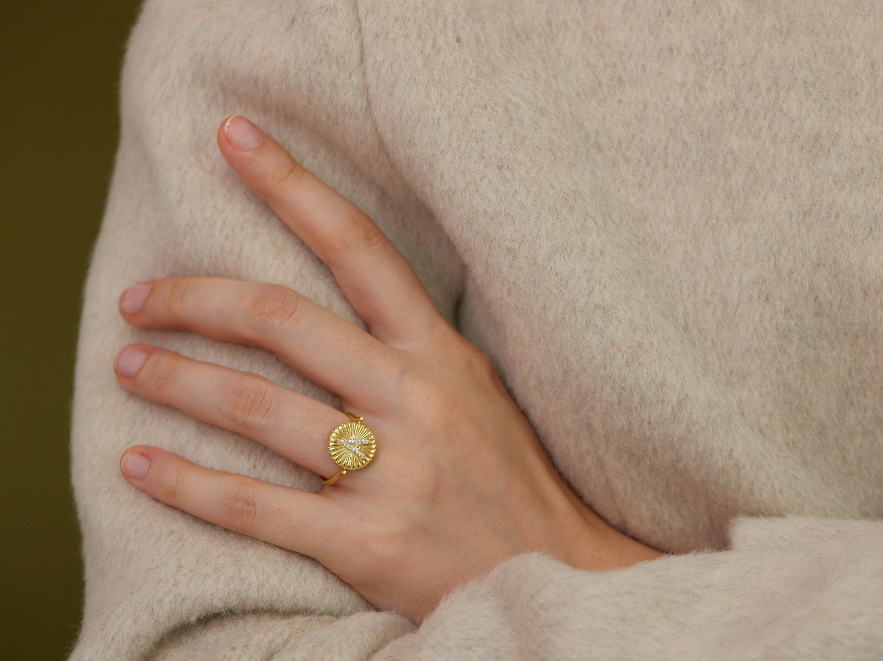 A close-up of a person&#39;s hand wearing a gold ring with a circular design.