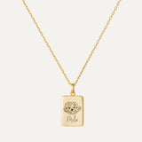 Gold necklace with a pendant featuring a dog illustration and engraved text on a white background