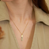 Gold necklace with a paw print pendant worn by a person in a beige shirt.